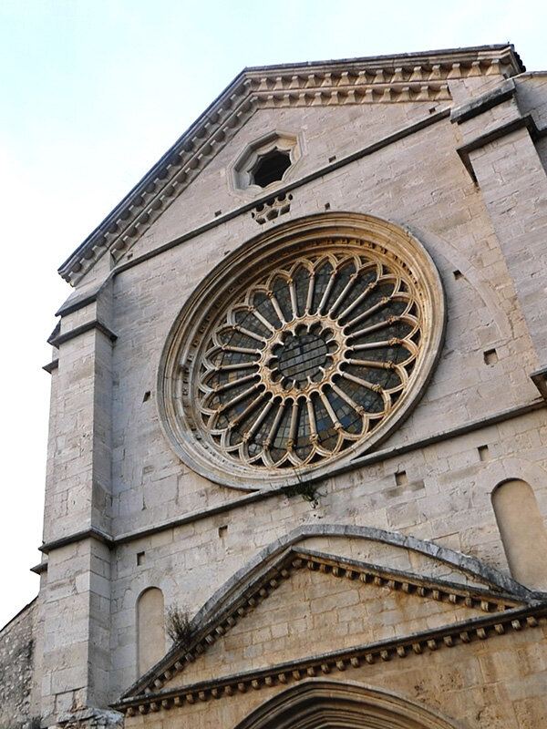 Facciata della chiesa dell'abbazia di Fossanova che mostra un grande rosone dettagliato e un arco d'ingresso ornato.