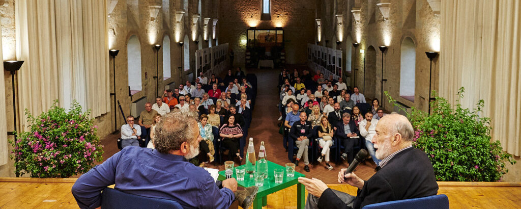 Conferenza giornalistica per la manifestazione Vini d'Abbazia sul vino ed i vitigni nell'abbazia di Fossanova con pubblico seduto in sala.
